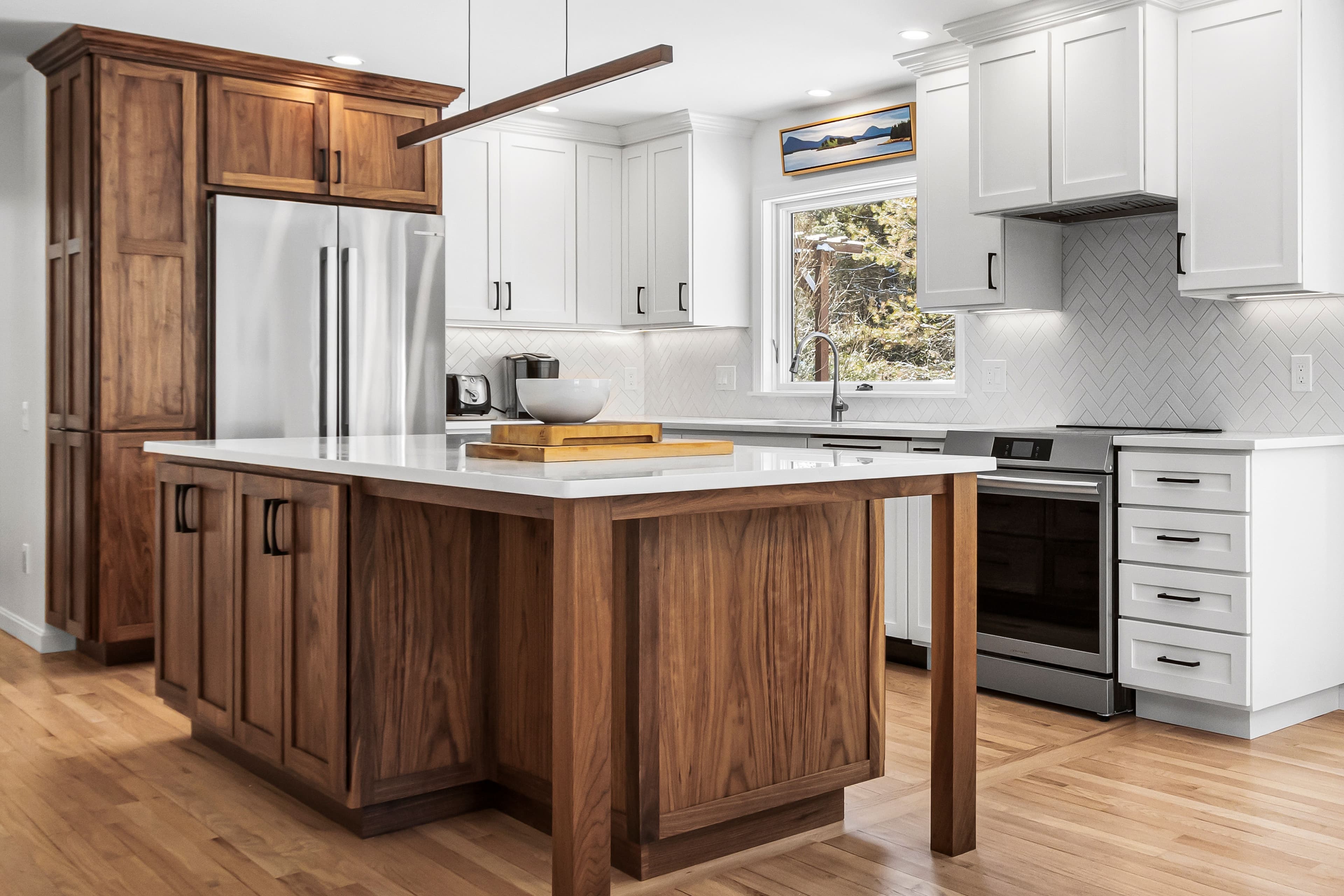 Custom kitchen remodel featuring walnut and marble island, walnut fridge enclosure with cabinets, and remaining cabinets painted white.